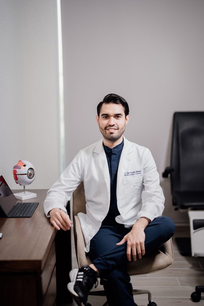 Dr. Alan Treviño en su escritorio con un modelo del ojo